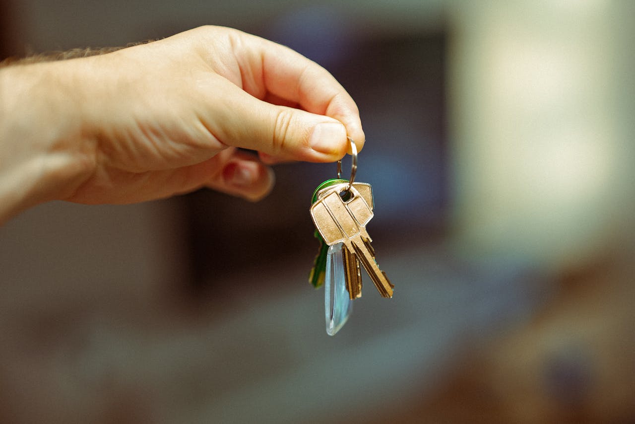 services-02 A close-up image of a hand holding a keyring with several house keys, symbolizing real estate and home ownership.